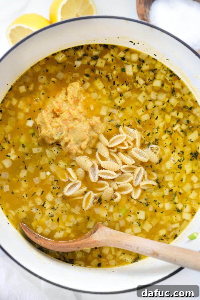 Sunshine Chickpea Bowl 13 The smooth, creamy pureed chickpea mixture and dried short pasta being added back into the actively simmering soup, ready to cook together.
