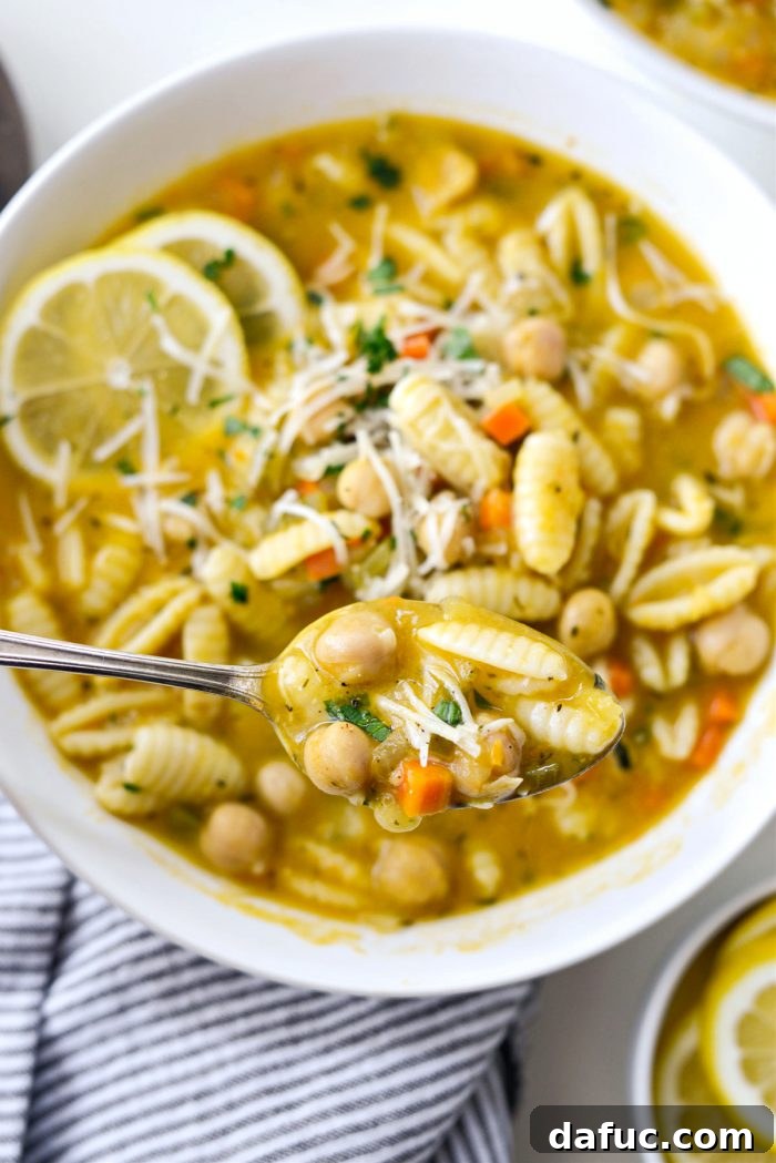 Sunshine Chickpea Bowl 19 A close-up shot of a spoonful of Lemon Chickpea Soup, highlighting the pasta, chickpeas, and broth with fresh herbs.