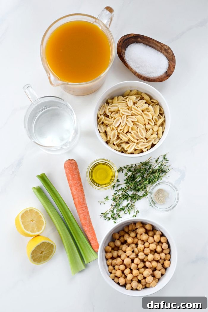 Sunshine Chickpea Bowl 4 An array of fresh ingredients for Lemon Chickpea Soup including lemons, chickpeas, carrots, celery, onion, thyme, and garlic-infused olive oil, neatly arranged on a wooden board.