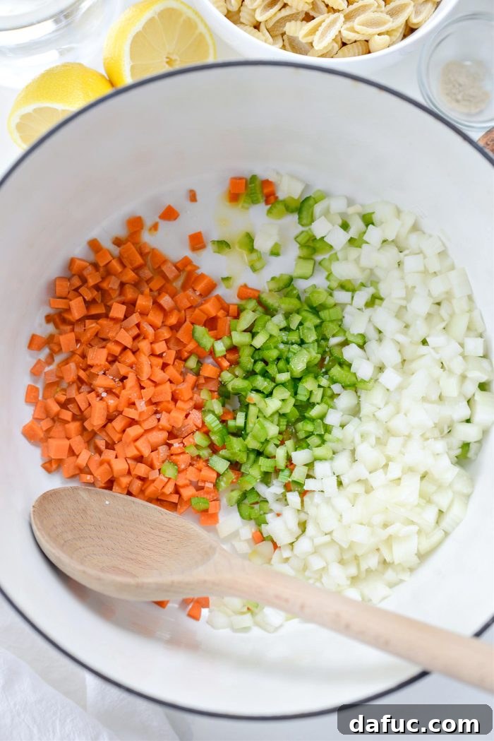 Sunshine Chickpea Bowl 5 Garlic infused olive oil, expertly diced carrot, celery, and yellow onion gently cooking in a robust dutch oven, creating the aromatic base for the soup.