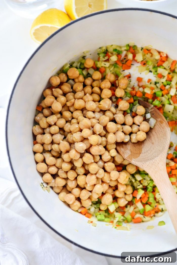 Sunshine Chickpea Bowl 8 Drained and thoroughly rinsed chickpeas being added to the fragrant, sautéed vegetables in the dutch oven, ready for the liquid base.