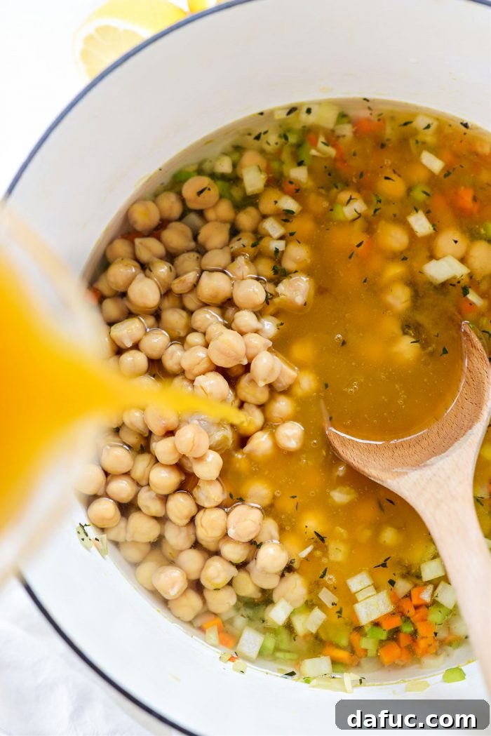 Sunshine Chickpea Bowl 9 A stream of clear vegetable broth and water cascading into the pot, joining the chickpeas and sautéed vegetables, ready to be brought to a simmer.