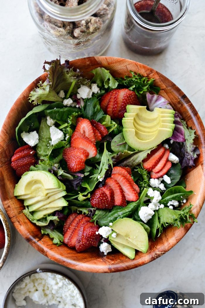 Adding sliced strawberries, avocado, and crumbled goat cheese to the spring greens