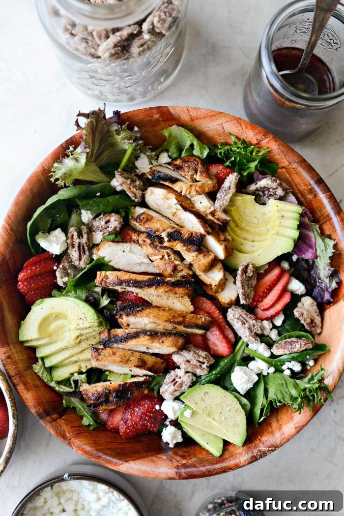 Topping the salad with grilled chicken slices and candied pecans