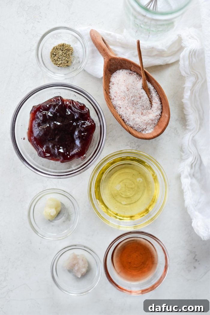 Ingredients for raspberry walnut vinaigrette, including jam, vinegar, oil, shallots, and garlic