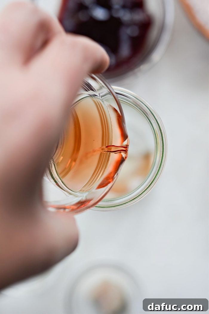 Pouring raspberry blush vinegar into a jar with salt