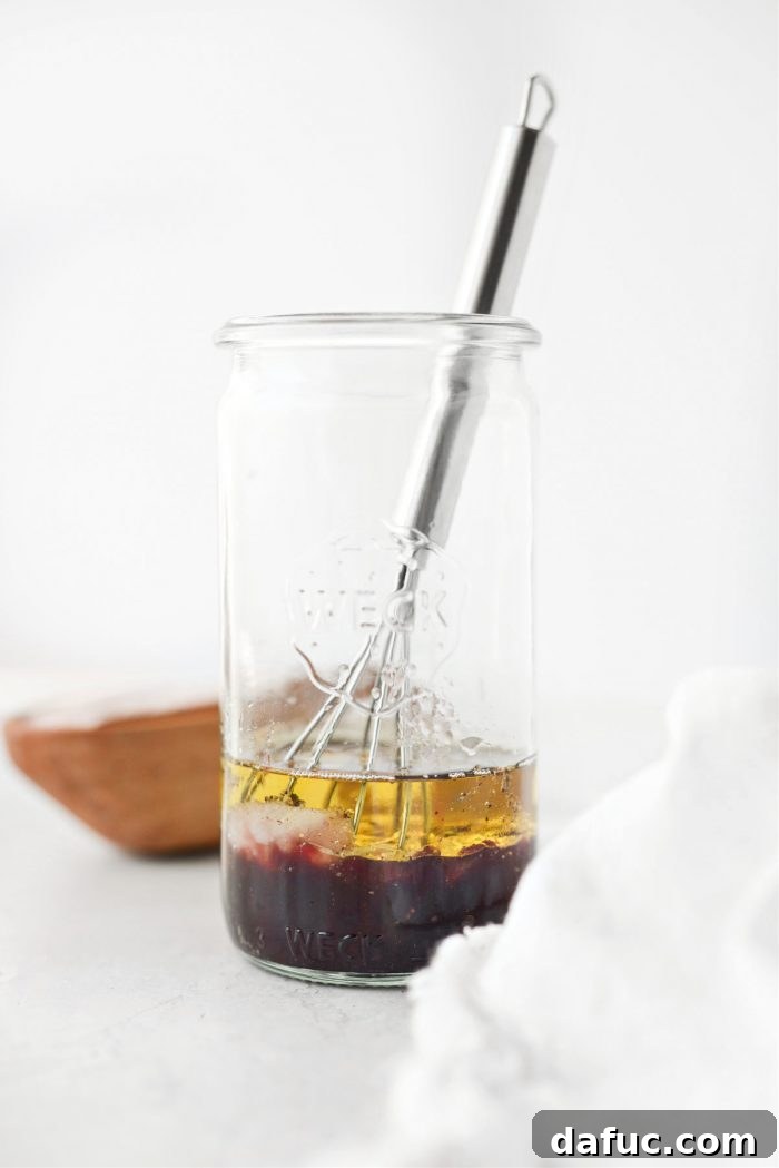 Adding remaining ingredients like jam, oil, shallot, and garlic to the jar for the dressing