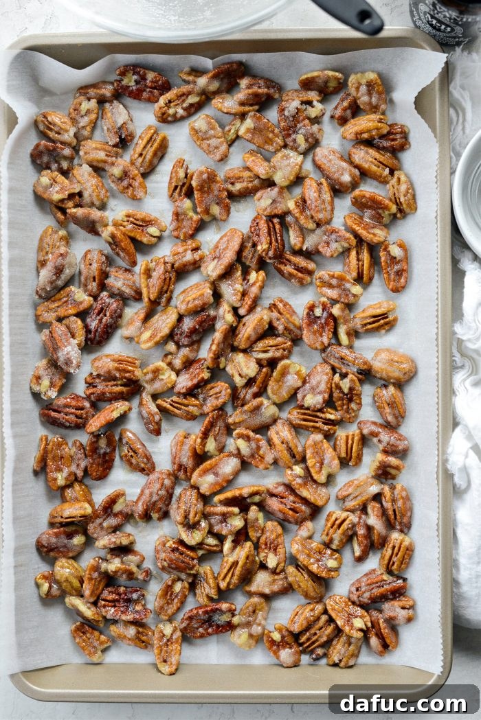 The baking sheet with pecans being placed into a preheated oven for the initial bake