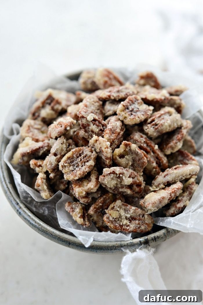 A glass container filled with freshly made candied pecans, ready for storage or serving