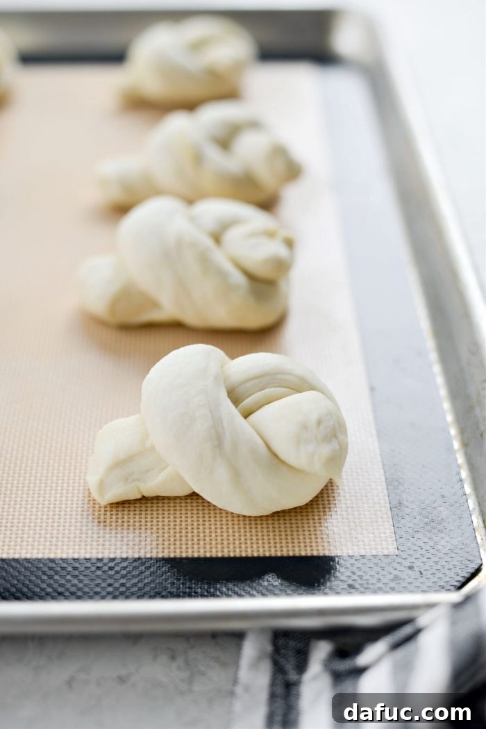 Shaped dough knots placed on a lined rimmed baking pan
