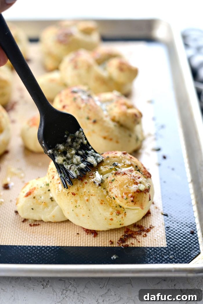 Freshly baked garlic herb knots being brushed with remaining butter mixture