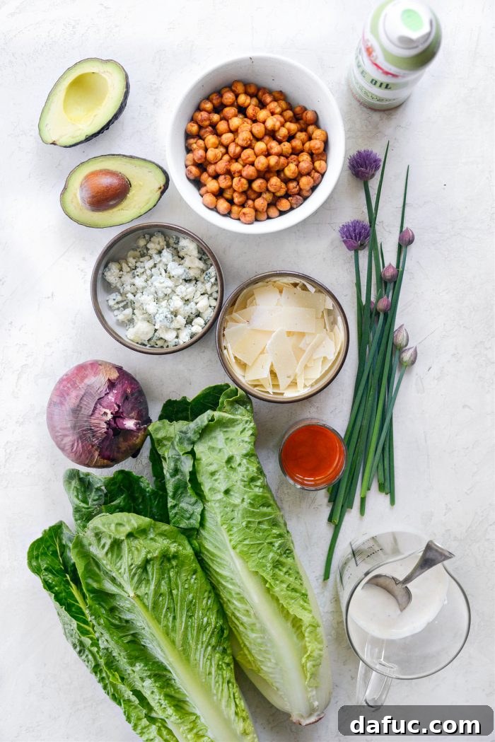 Ingredients for Air Fryer Buffalo Chickpea Caesar Salad displayed on a cutting board.