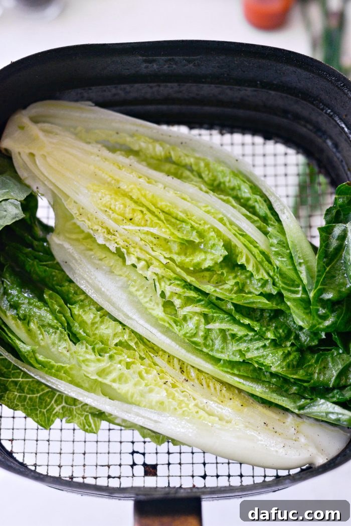Romaine lettuce halves placed neatly in an air fryer basket, ready for cooking.