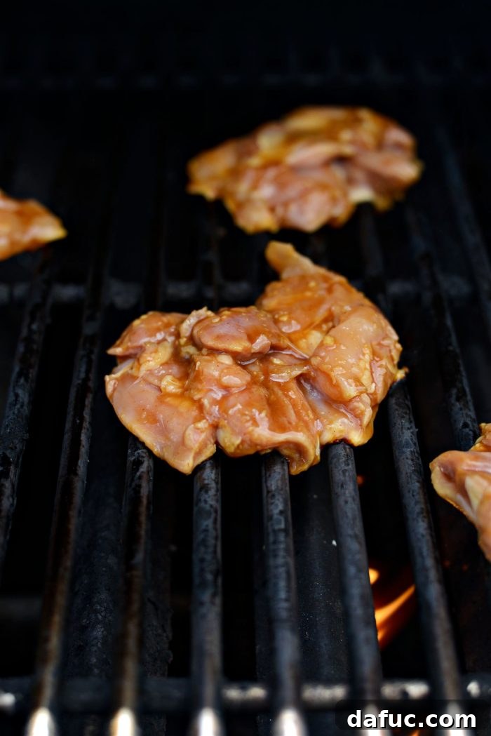 Huli Huli chicken thighs sizzling on hot grill grates, starting to char