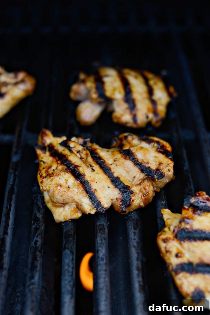 Grilled Huli Huli chicken thighs being turned on the grill, showing a sticky, caramelized side