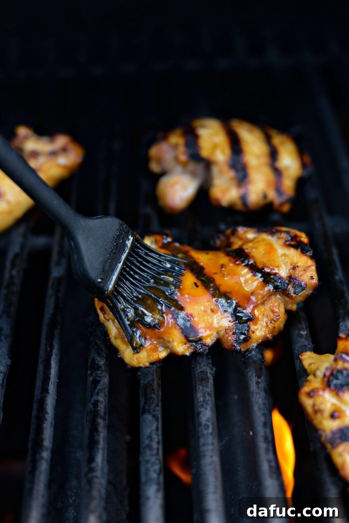 Brushing grilled Huli Huli chicken with the reserved marinade to create a glossy glaze