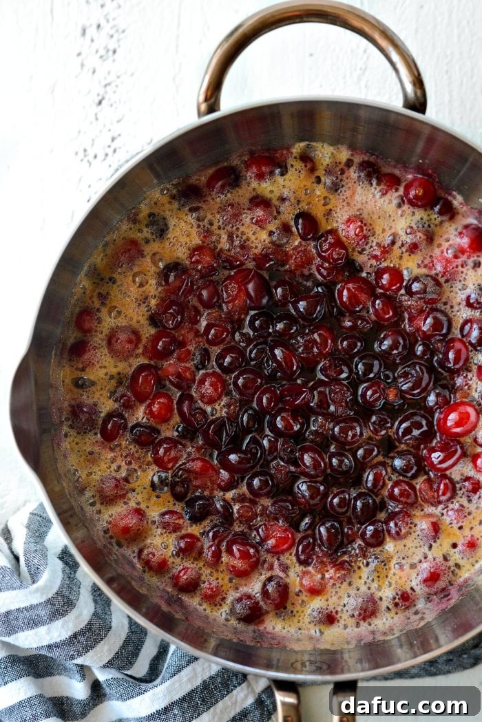 cranberries simmering in the saucepan, bursting and softening