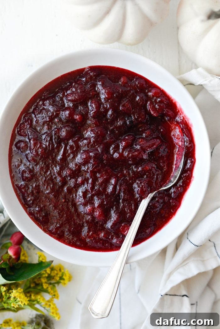homemade cranberry sauce in a white bowl with a silver spoon