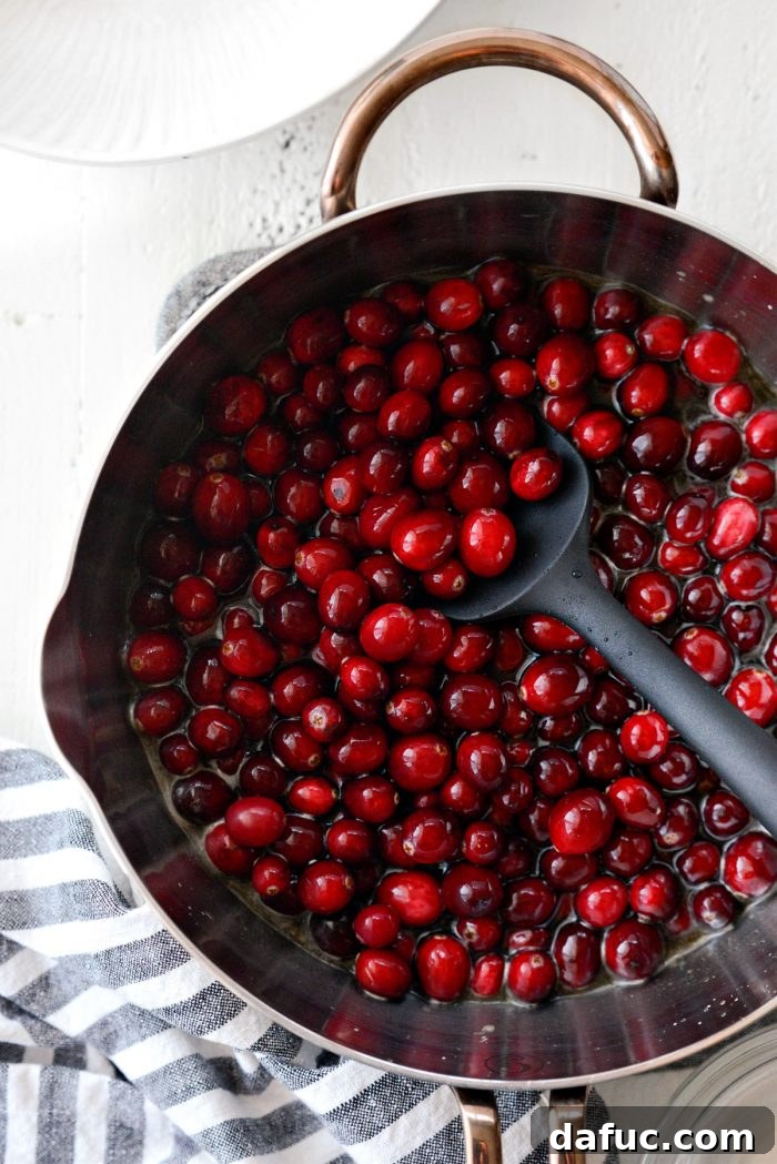fresh cranberries added to the simmering liquid in a saucepan