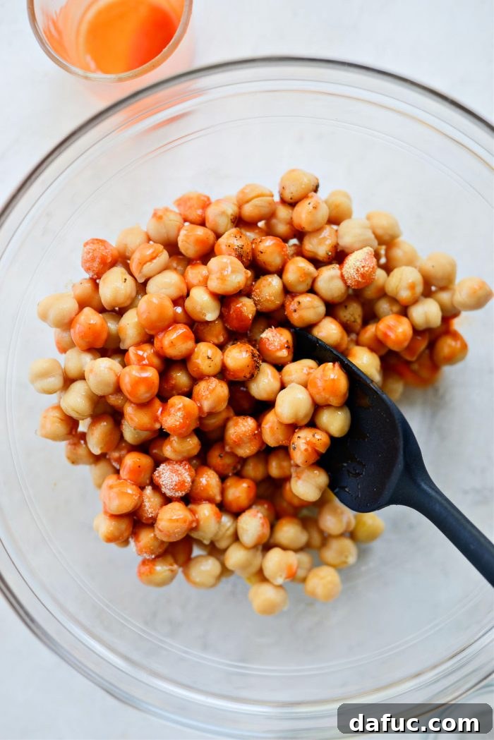 Tossing chickpeas with buffalo sauce and seasonings to combine