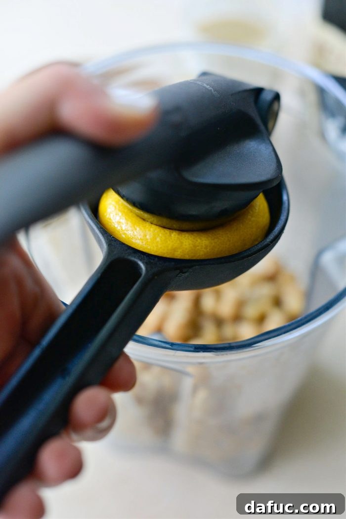 Velvet Smooth Blender Hummus 9 Squeezing fresh lemon juice into a blender with hummus ingredients