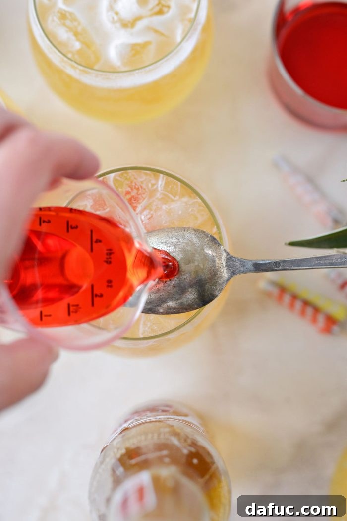 Tropical Tequila Sunrise Shandy 13 Slowly pouring grenadine over the back of the spoon, creating layers in the cocktail