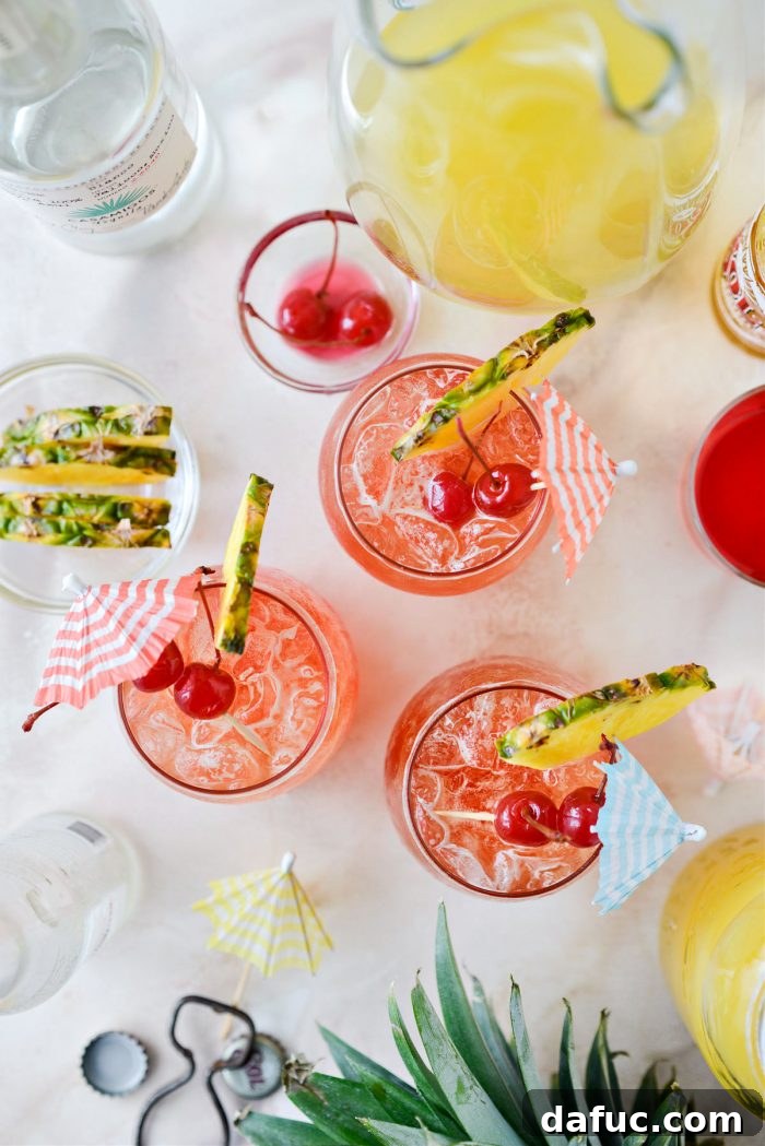 Tropical Tequila Sunrise Shandy 15 Pineapple Tequila Sunrise Shandy garnished with pineapple slices and maraschino cherries