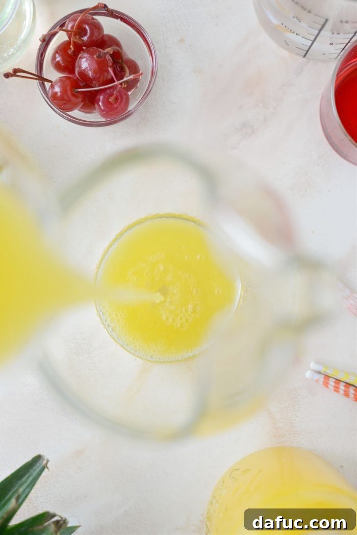 Tropical Tequila Sunrise Shandy 5 Pouring chilled pineapple juice into a mixing pitcher