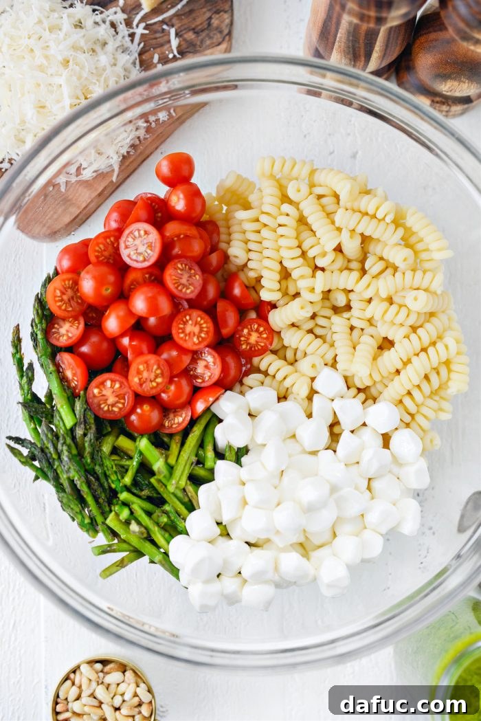 cooked pasta, cherry tomatoes, asparagus and mozzarella in bowl.
