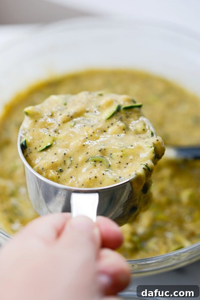 Measuring cup filled with zucchini bread batter, ready for pouring into pans