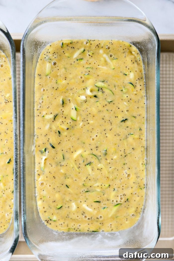 Zucchini bread batter divided into two loaf pans, ready for baking