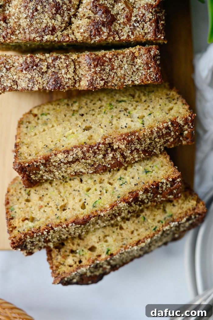 A perfectly sliced piece of Lemon Poppy Seed Zucchini Bread showing its moist crumb and poppy seeds