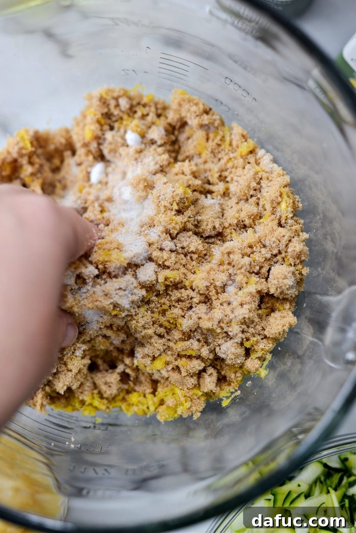 Hands massaging lemon zest into the sugars to infuse flavor