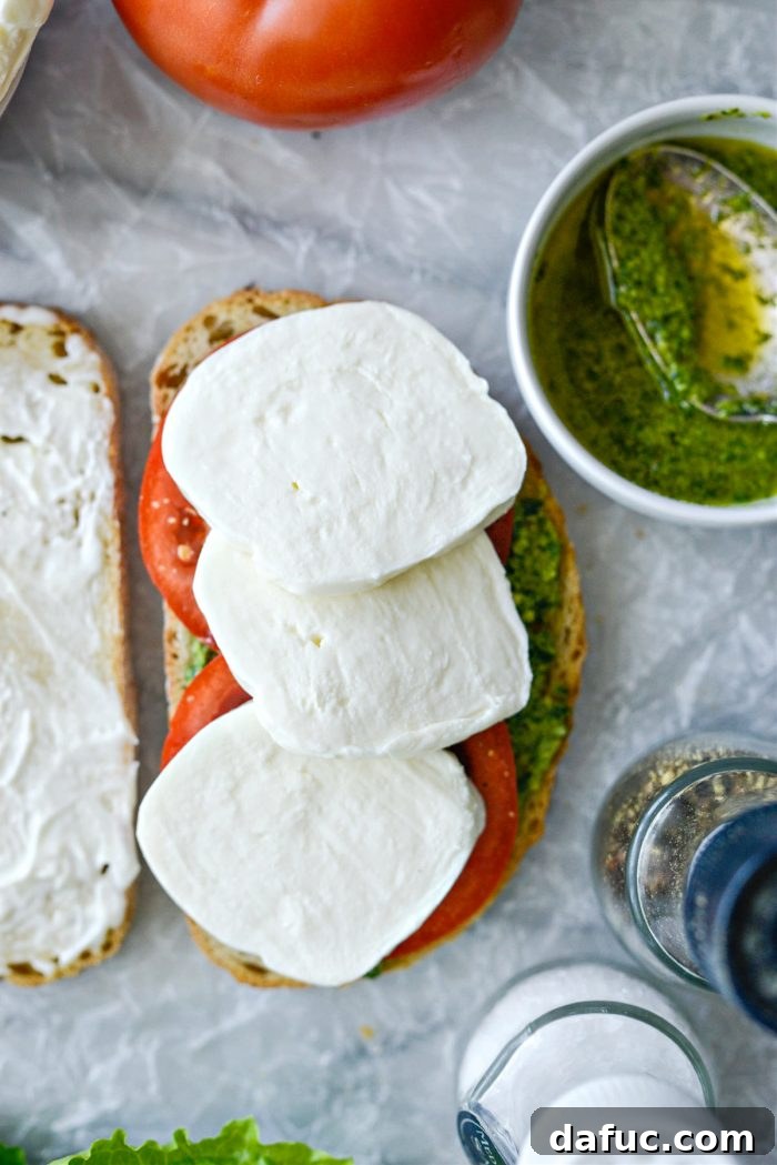 Adding fresh mozzarella slices over the tomato and pesto