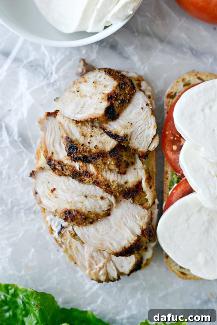 Layering sliced grilled turkey on the mayonnaise side of the bread