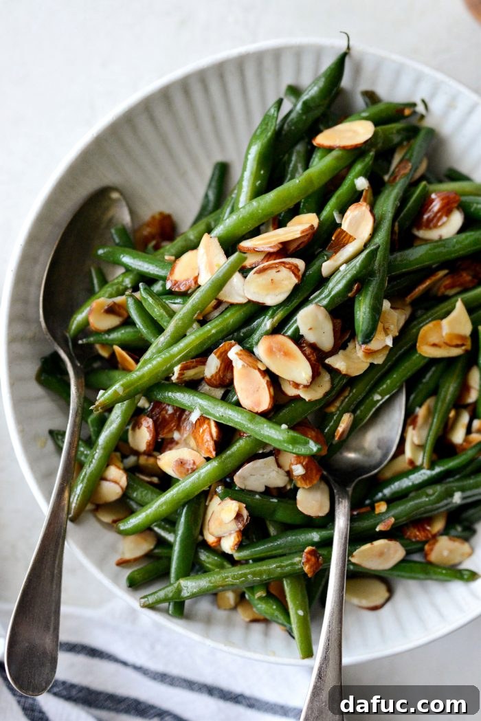 garlicky green beans almondine in cream colored bowl.
