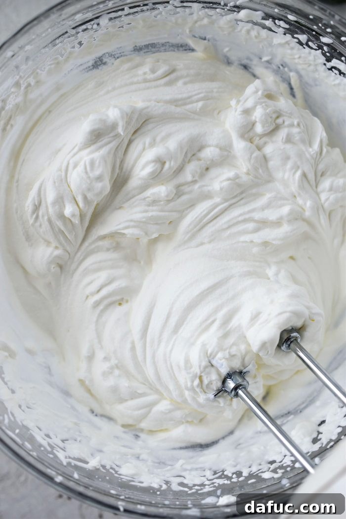 Blissful No-Churn Hash Indulgence 11 Creamy stiff peaks of whipped heavy cream in a mixing bowl