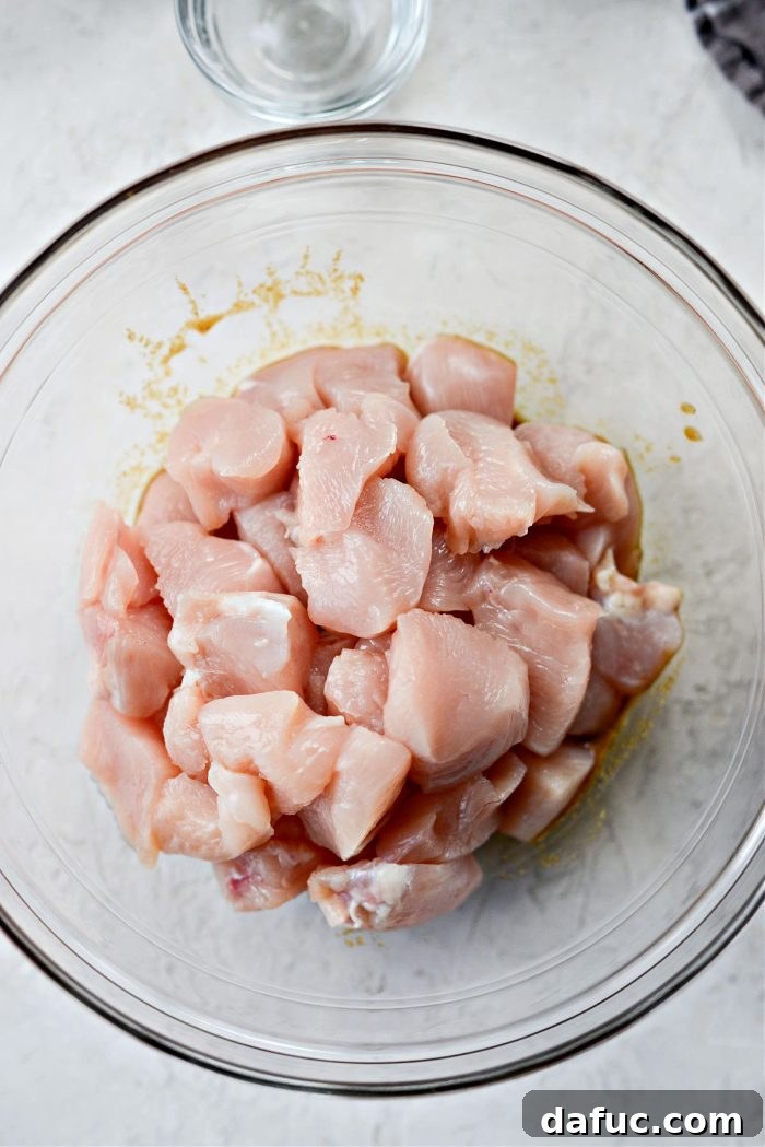 Diced chicken added to marinade in a bowl