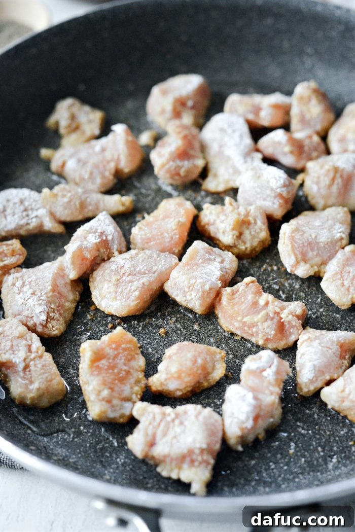 Coated chicken pieces added to a hot skillet