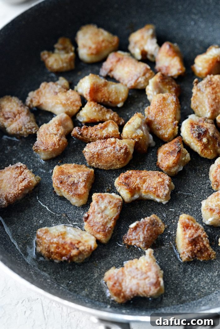 Browned chicken pieces cooking in a skillet