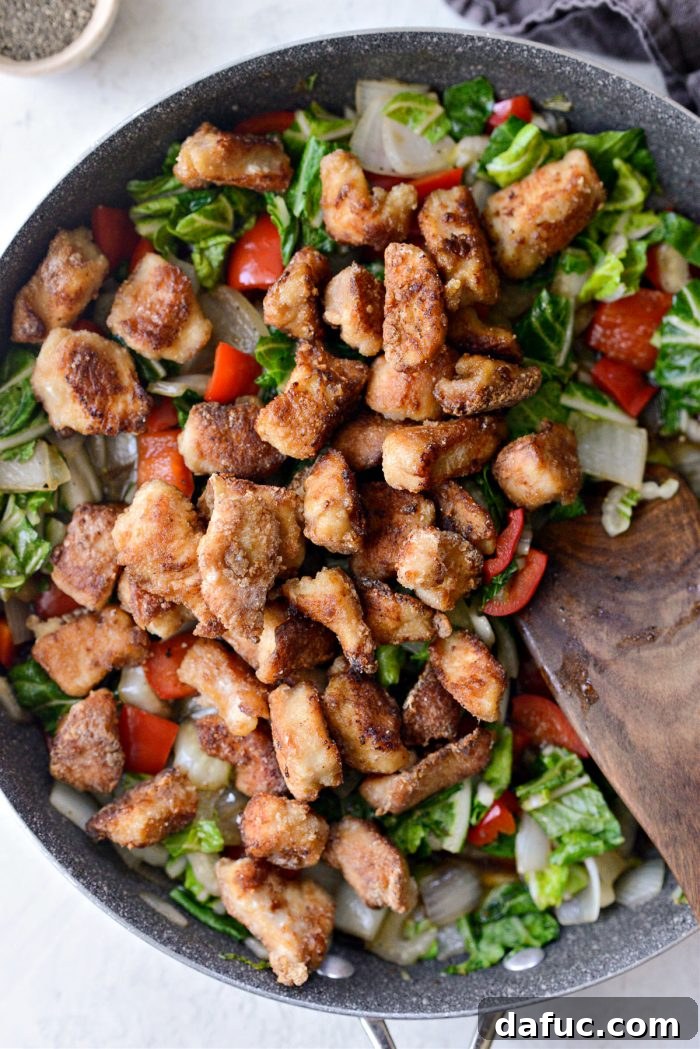 Cooked crispy chicken pieces added back to the pan with vegetables and sauce