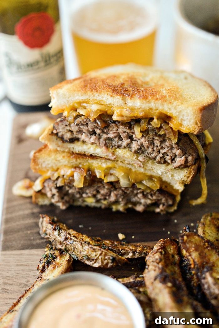 The Ultimate Beef Patty Melt 19 Two halves of a delicious Classic Beef Patty Melt presented on a rustic wooden cutting board