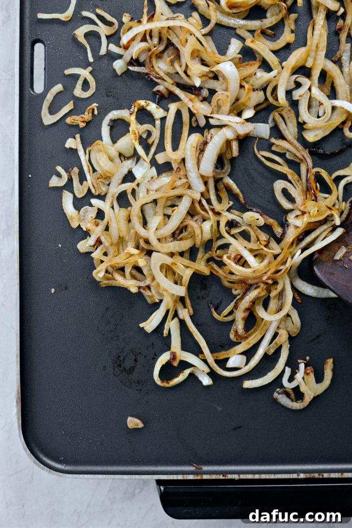 The Ultimate Beef Patty Melt 8 Softened and browned sautéed onions cooking on the griddle, showing the caramelization
