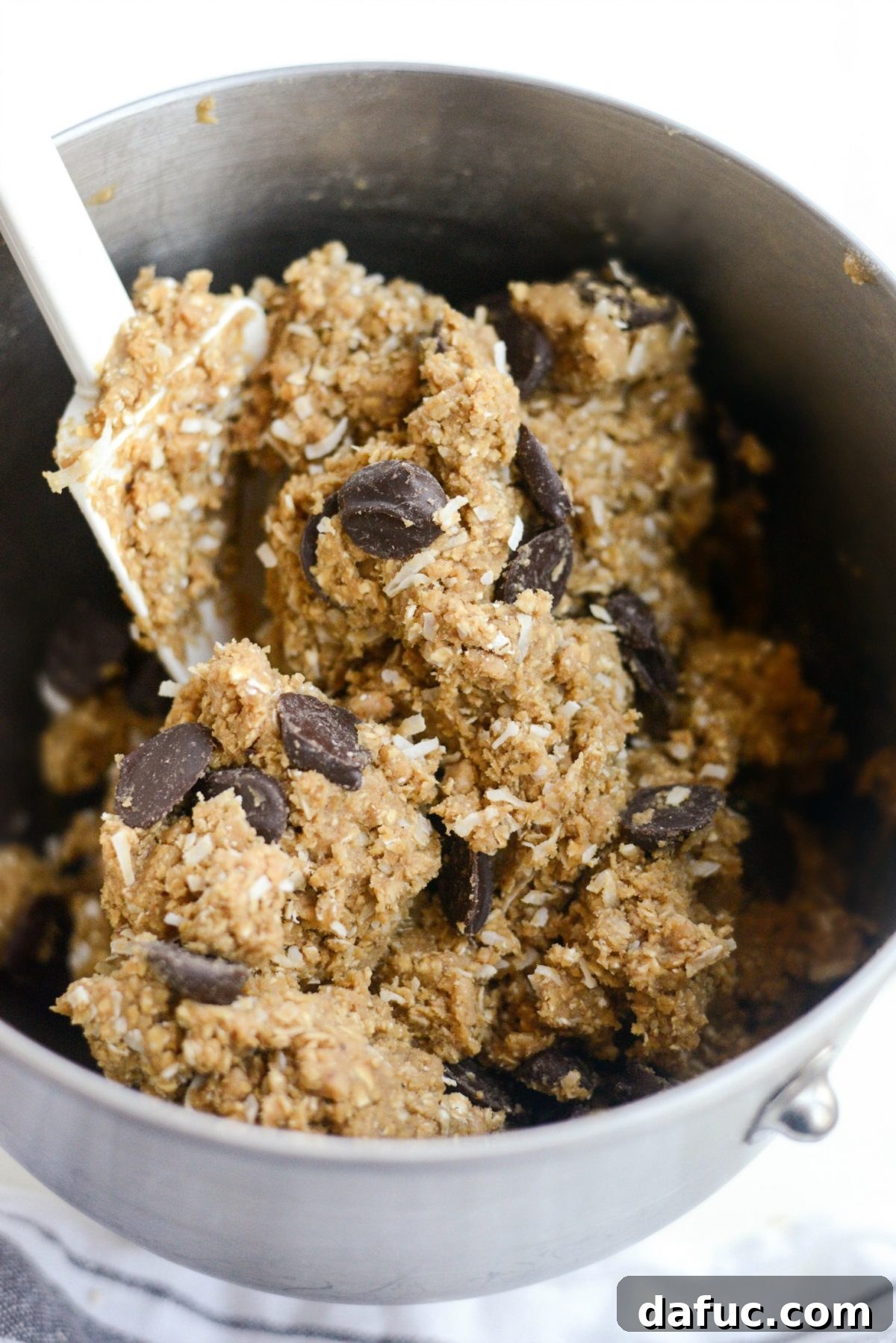 Golden Toffee Oatmeal Chocolate Chip Cookies 17 A bowl filled with rich cookie dough, generously studded with chocolate chips, toffee bits, and coconut flakes.