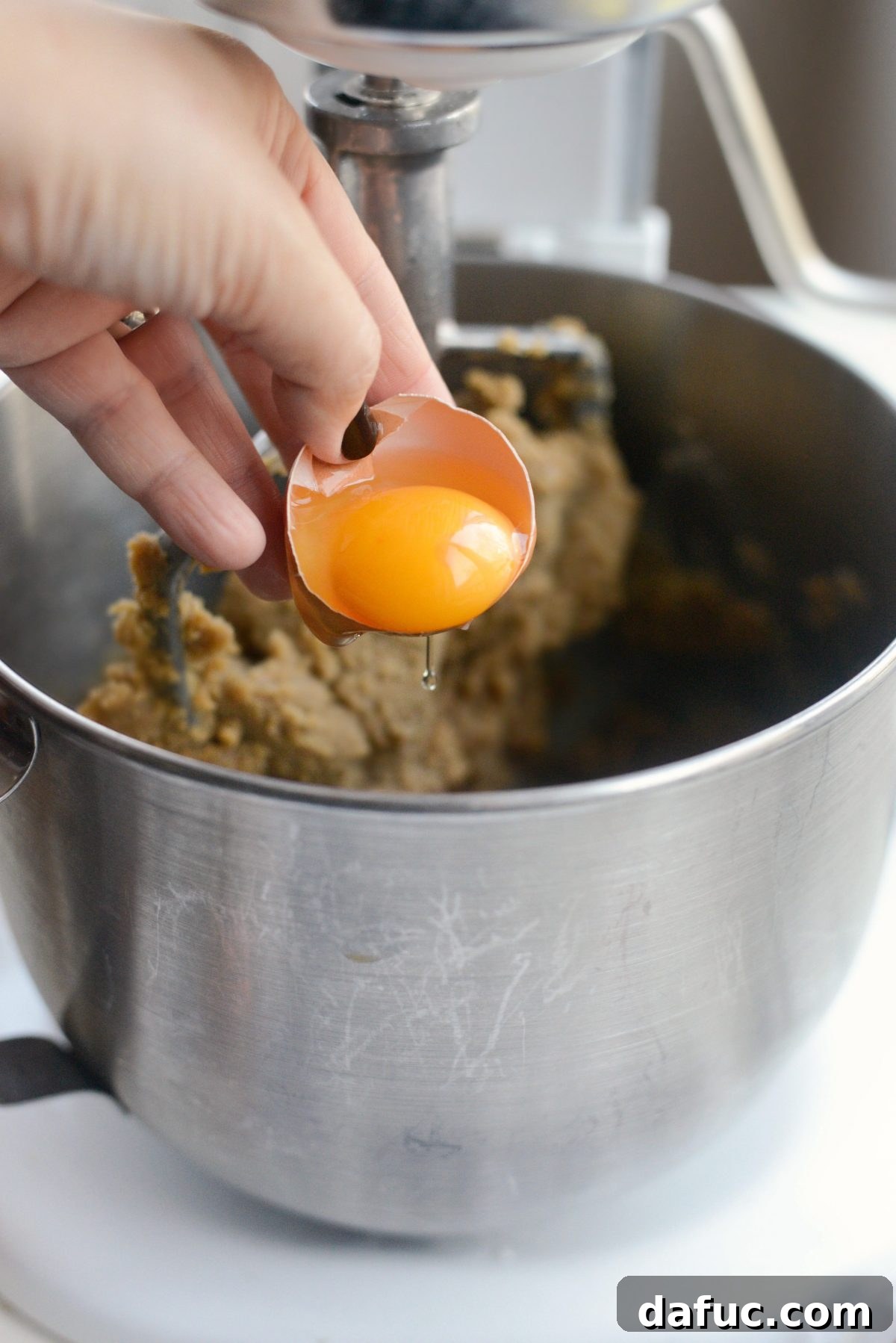 Golden Toffee Oatmeal Chocolate Chip Cookies 10 Cracking an egg into the cookie dough mixture in a stand mixer.