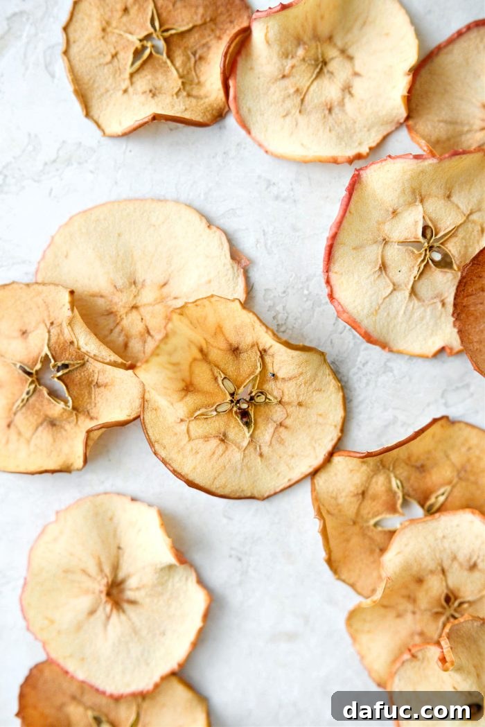 A final close-up shot of perfectly golden and crispy baked apple chips, glistening slightly