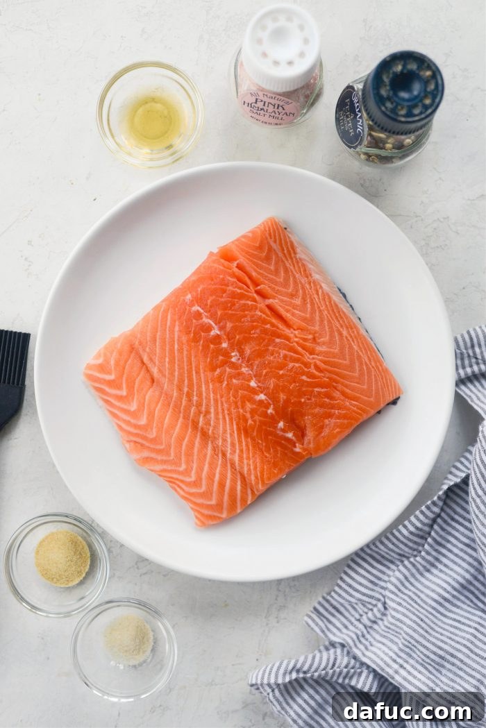 Easy Air Fryer Salmon 3 Close-up shot of fresh salmon filet, avocado oil, and spices laid out as ingredients for air fryer salmon.