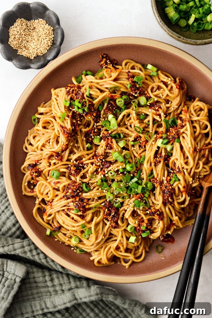 Fiery Garlic Sesame Noodles 2 A vibrant bowl of Spicy Garlic Sesame Noodles, garnished with chopped green onions and sesame seeds, ready to be enjoyed.