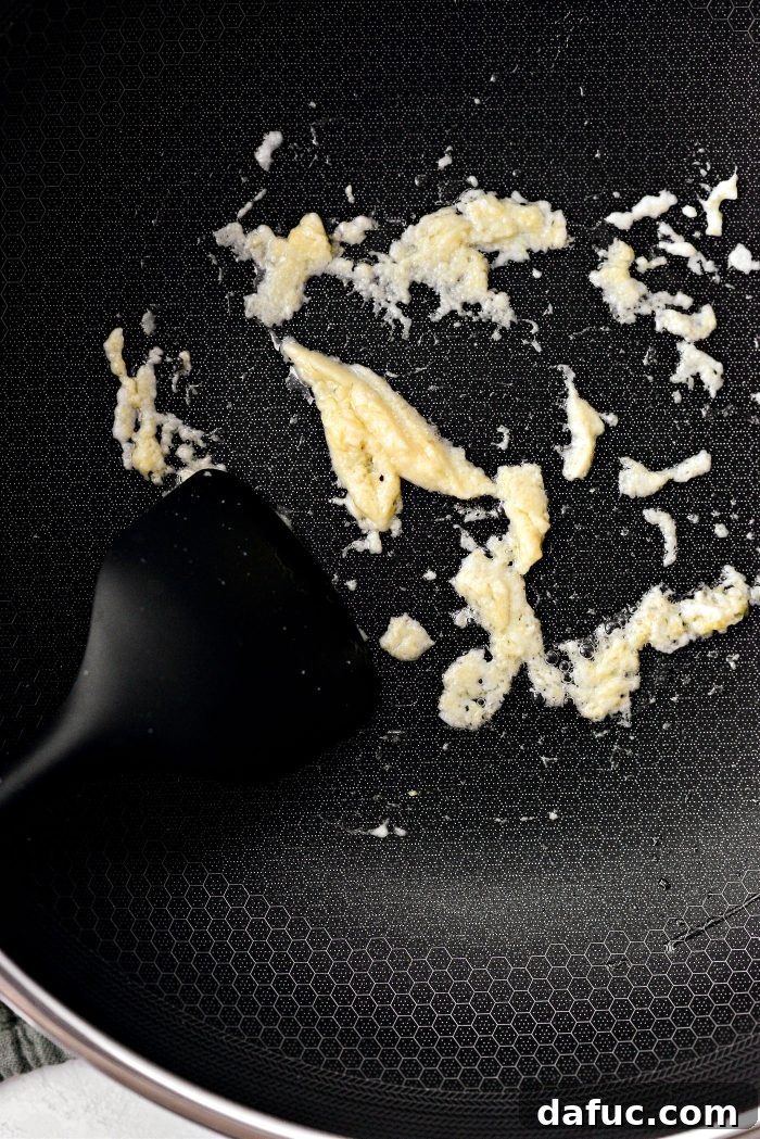 Fiery Garlic Sesame Noodles 12 A spatula stirring garlic and ginger paste in a wok for one minute to release their aromas.