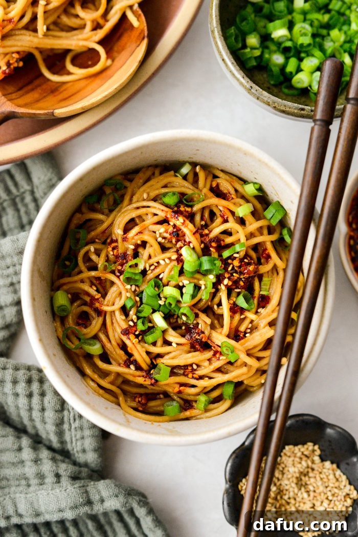 Fiery Garlic Sesame Noodles 17 A stunning side shot of Spicy Garlic Sesame Noodles, highlighting the generous sauce coating and fresh green onion garnish.